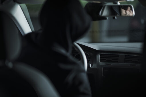 Grand Theft Auto Concept Photo with Caucasian Thief in His 30s Already Inside Stolen Car Taking Look in a Back Mirror. Automotive Theme.